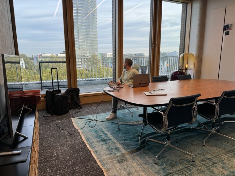a meeting room filled with furniture and a large window where dominik sitting on a chair is enjoying the view